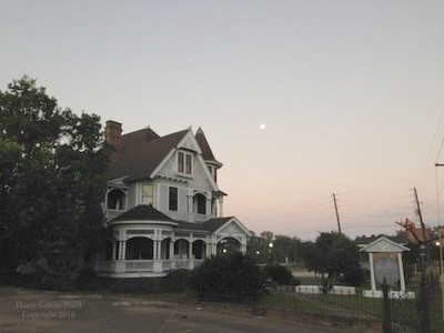 A private home with the moon setting in the distance