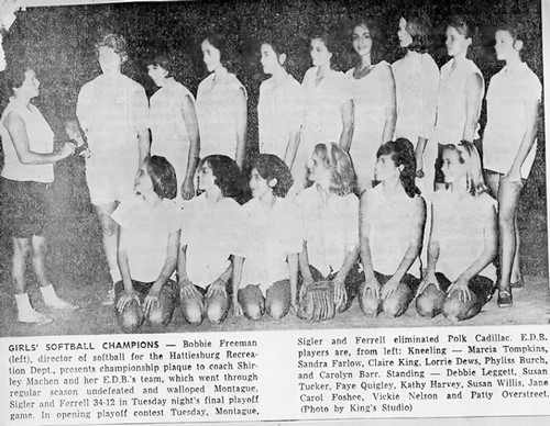A girls softball team poses with their coach
